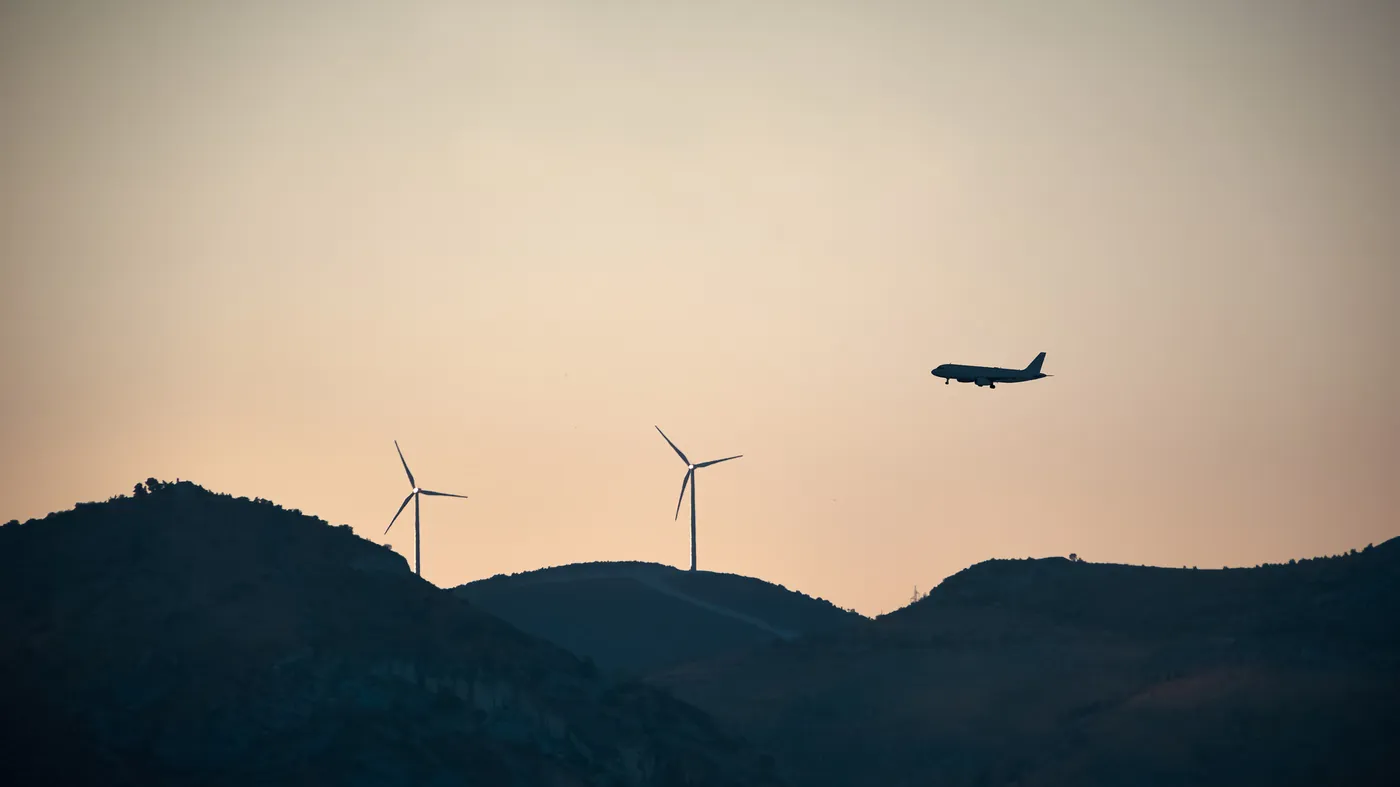 A jet crossing a sunset sky above a line of hills