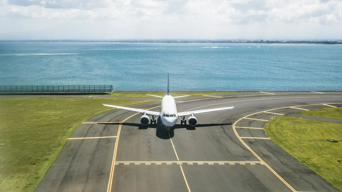 A passenger airliner taxiing on a runway beside the sea