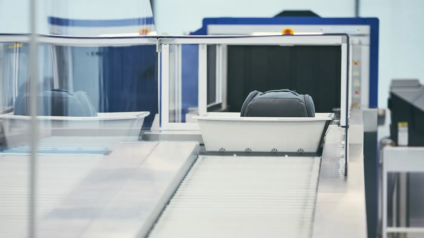 A bag in a tray on an airport security scanner belt