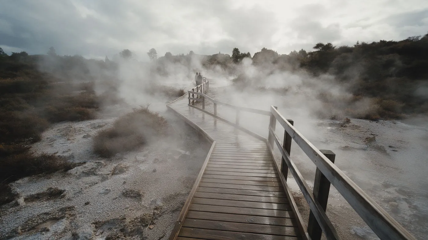 A wooden boardwalk through steaming geothermal ground