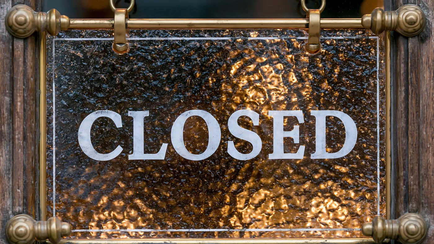 A closed sign hanging behind a glass door