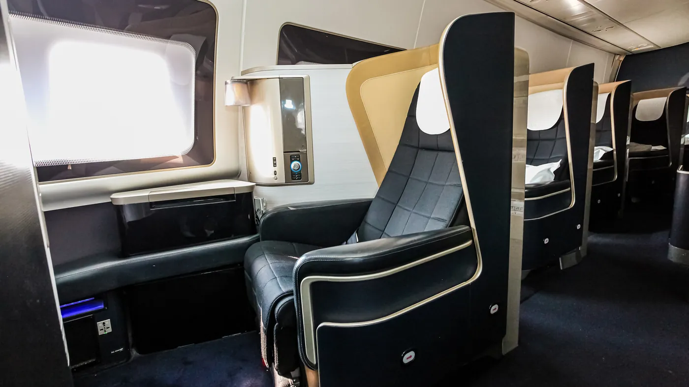 Empty premium-cabin seats with privacy dividers on a long-haul airliner