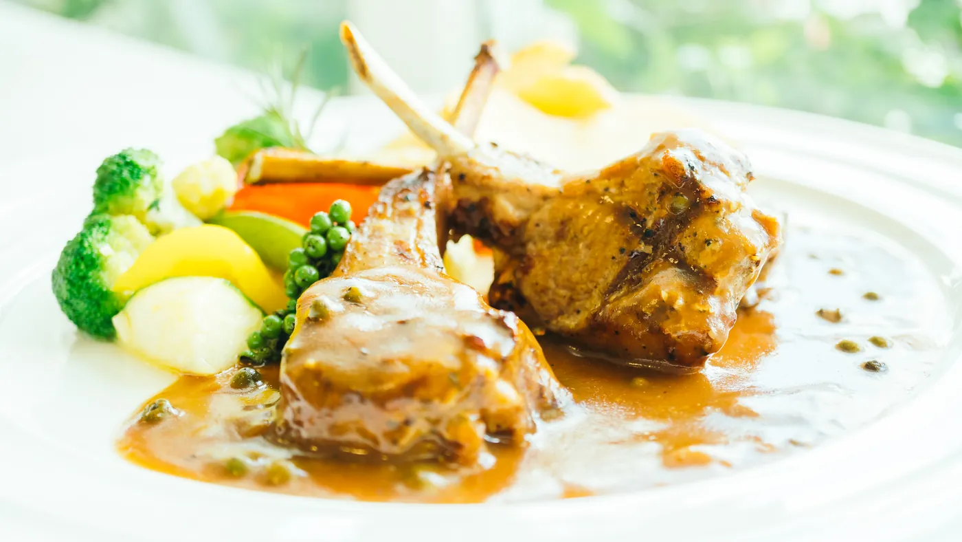 Grilled lamb cutlets with vegetables on a white plate