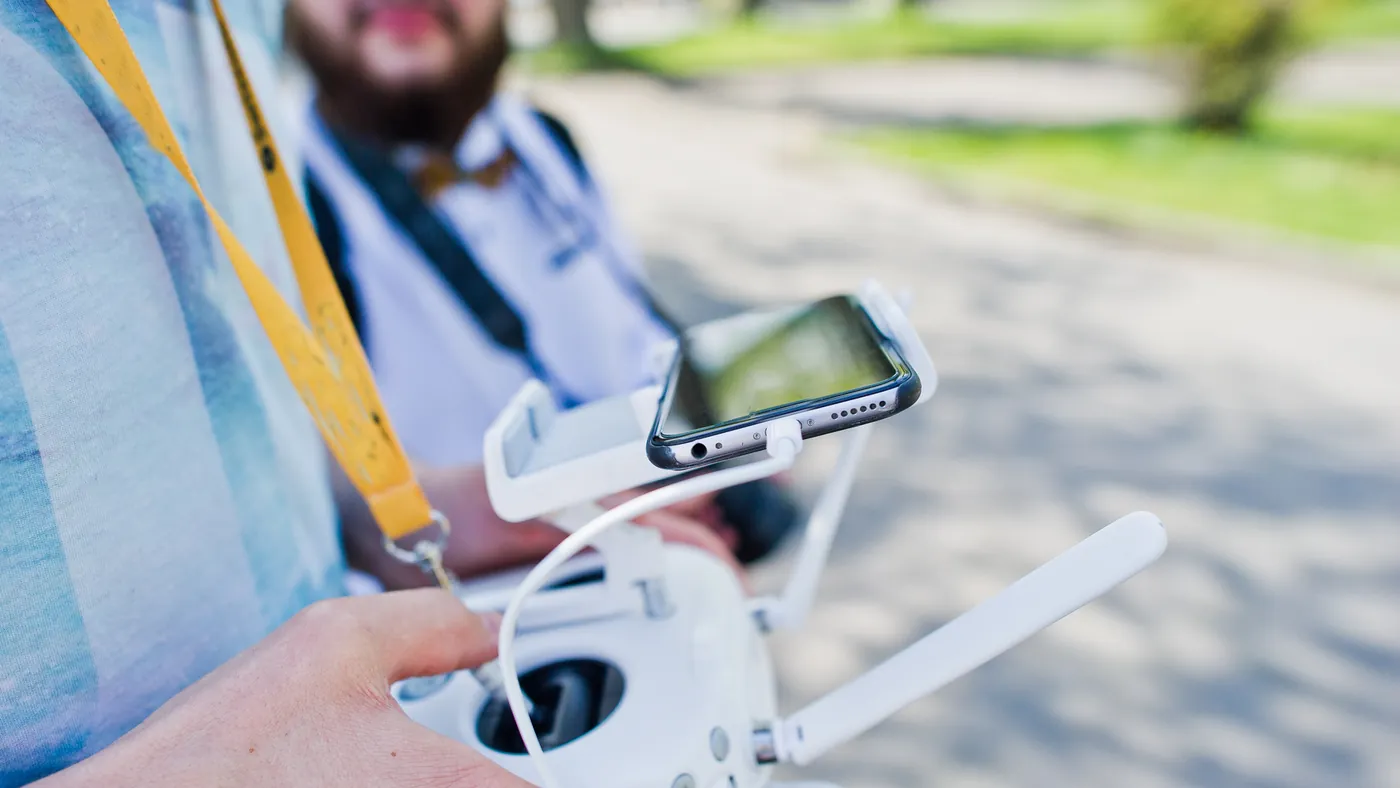 Hands holding a drone remote controller with a phone attached as a screen