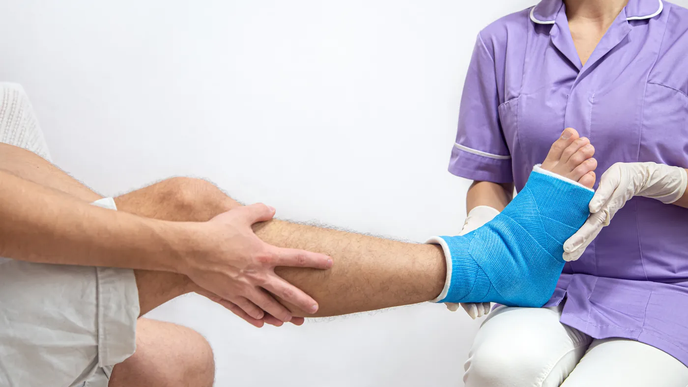A nurse holding a leg in a blue splint after treatment
