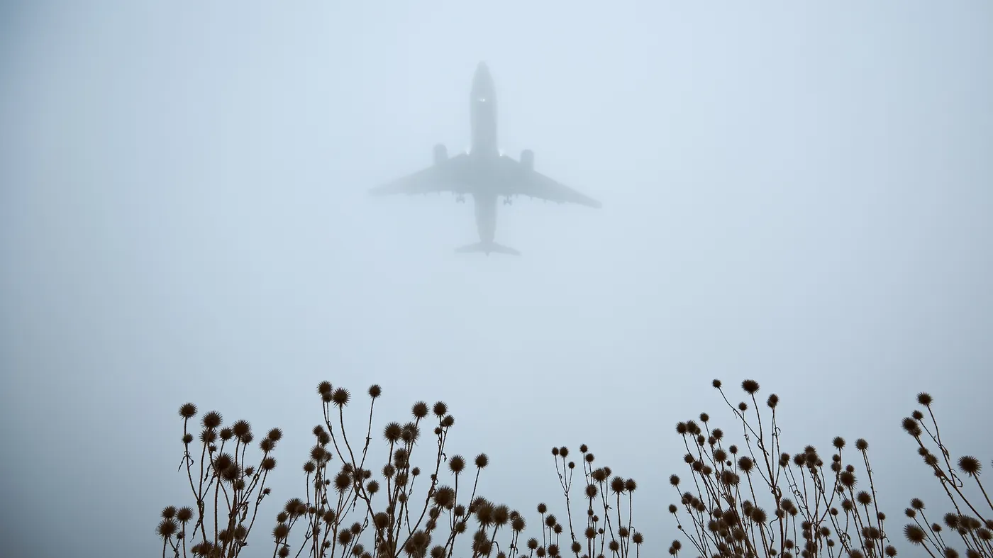 A passenger jet descending through grey cloud