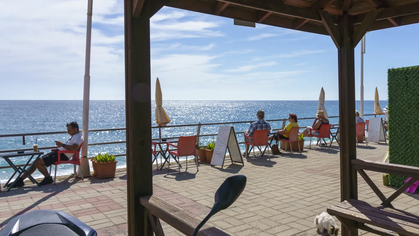 Diners at a seaside café terrace on a sunny day