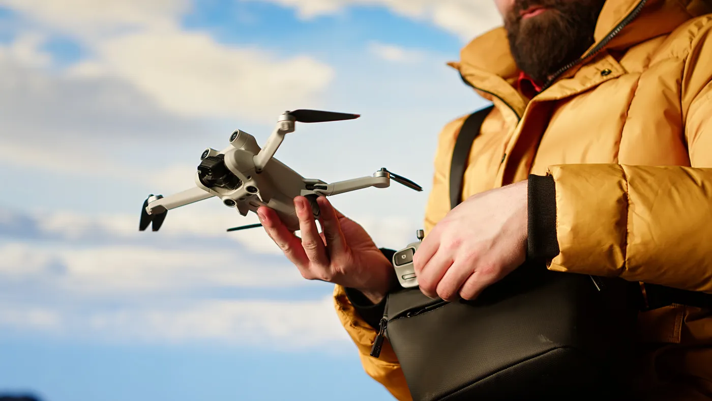A traveller holding a small folding drone ready to launch outdoors