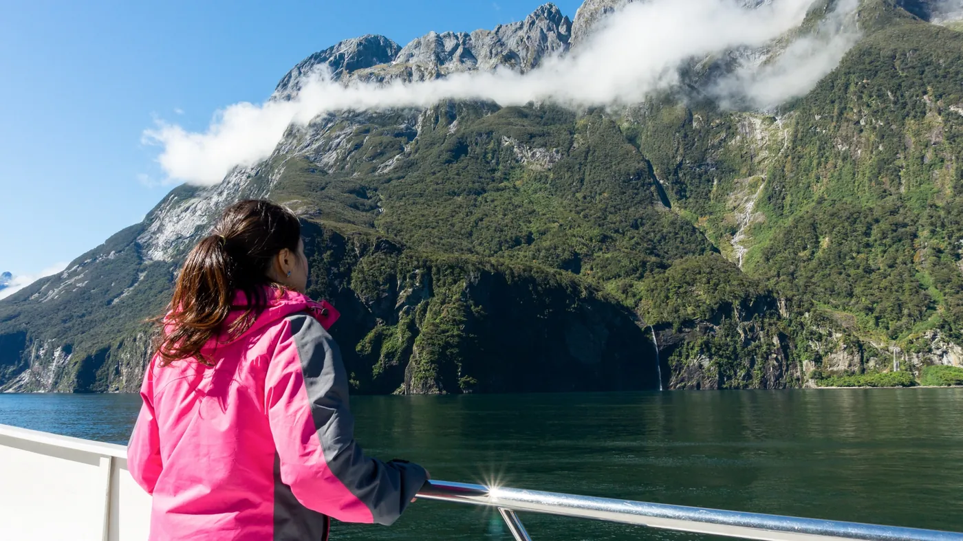 A traveller on the deck of a cruise boat in Milford Sound, New Zealand
