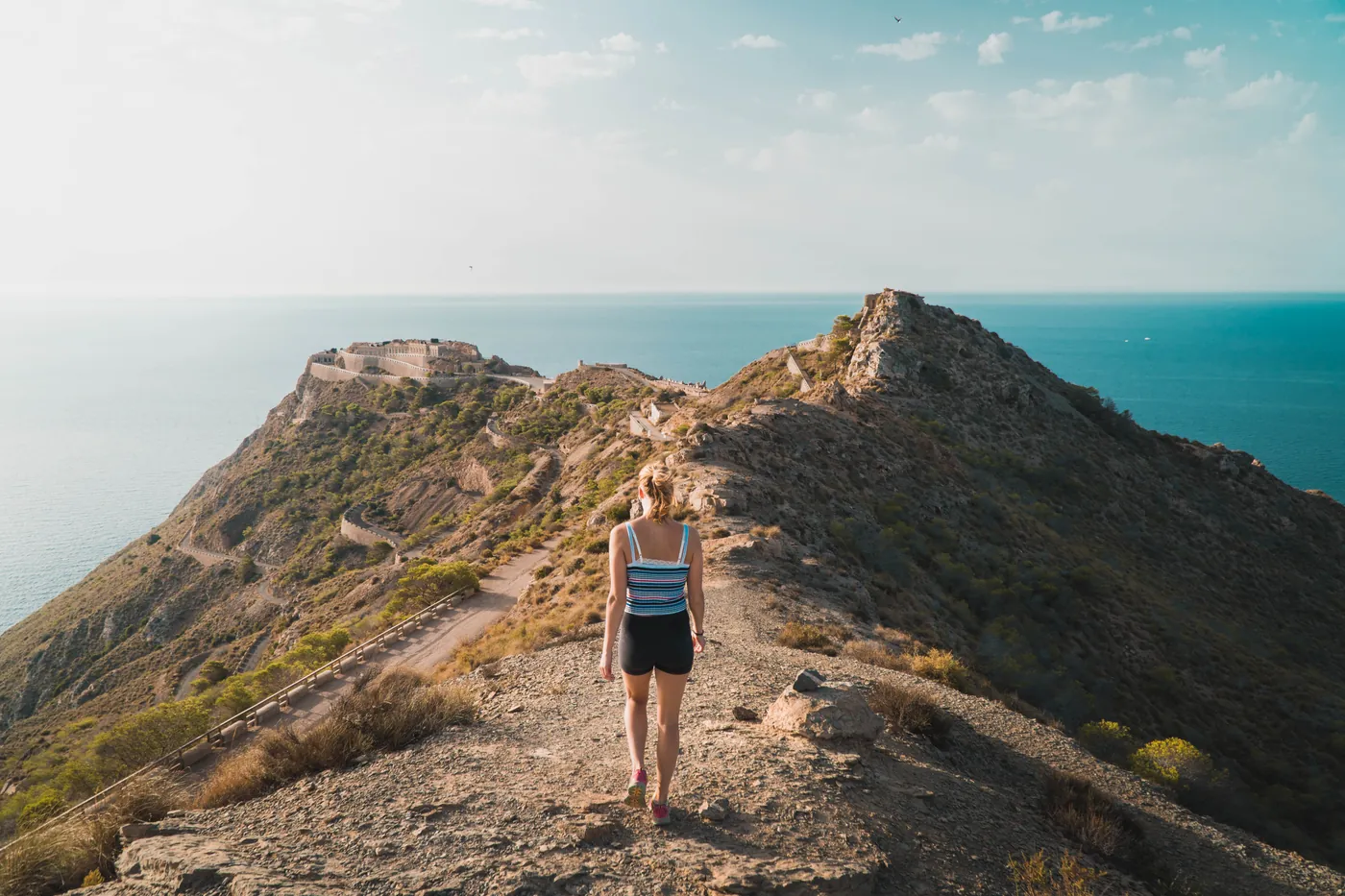 A walker on a gravel track along a headland above the sea