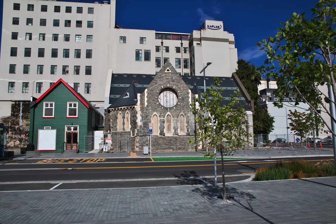 A restored stone church and a timber cottage on a Christchurch street