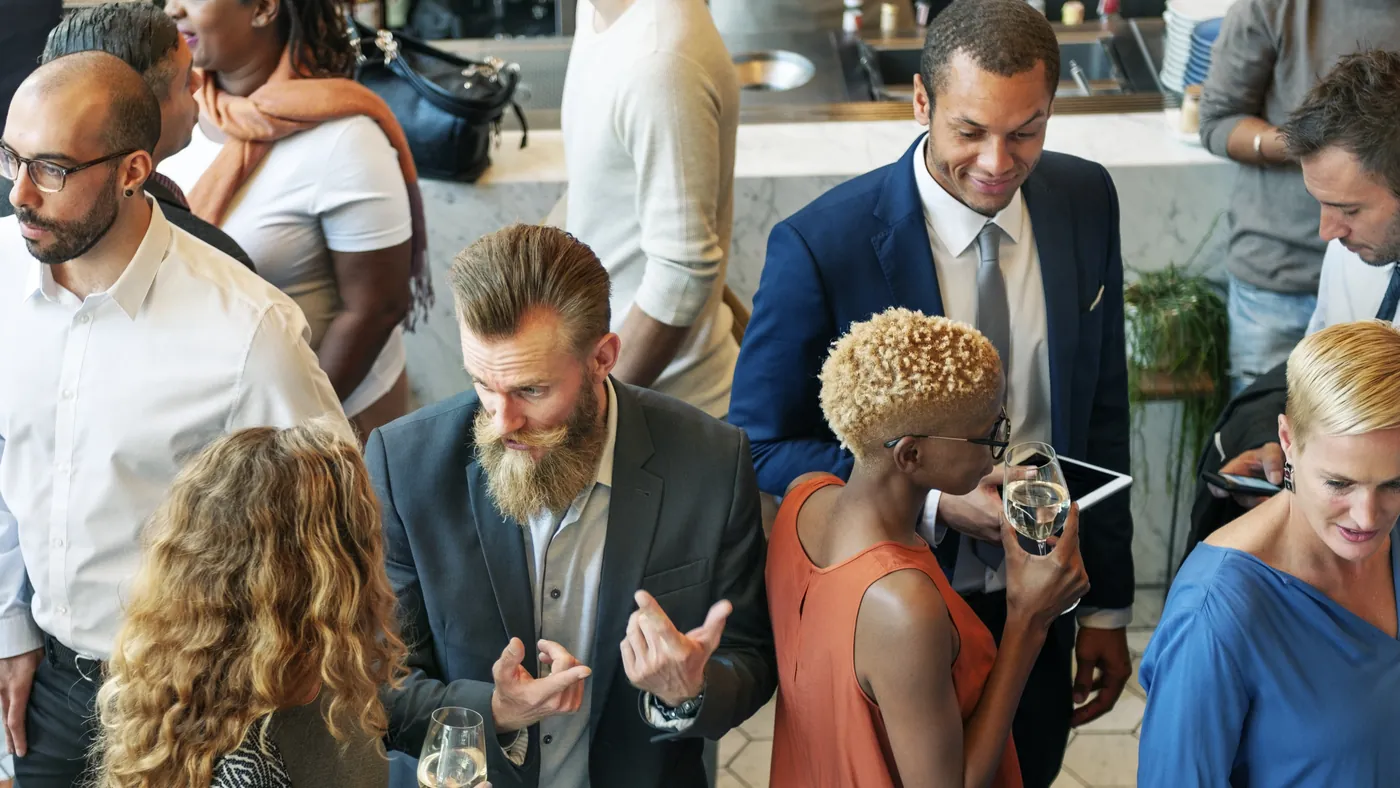 Guests in smart clothes talking and holding drinks at an evening reception