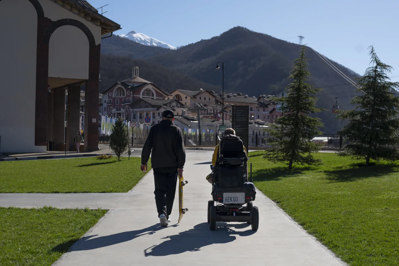 A man with a friend who uses a wheelchair, outdoors