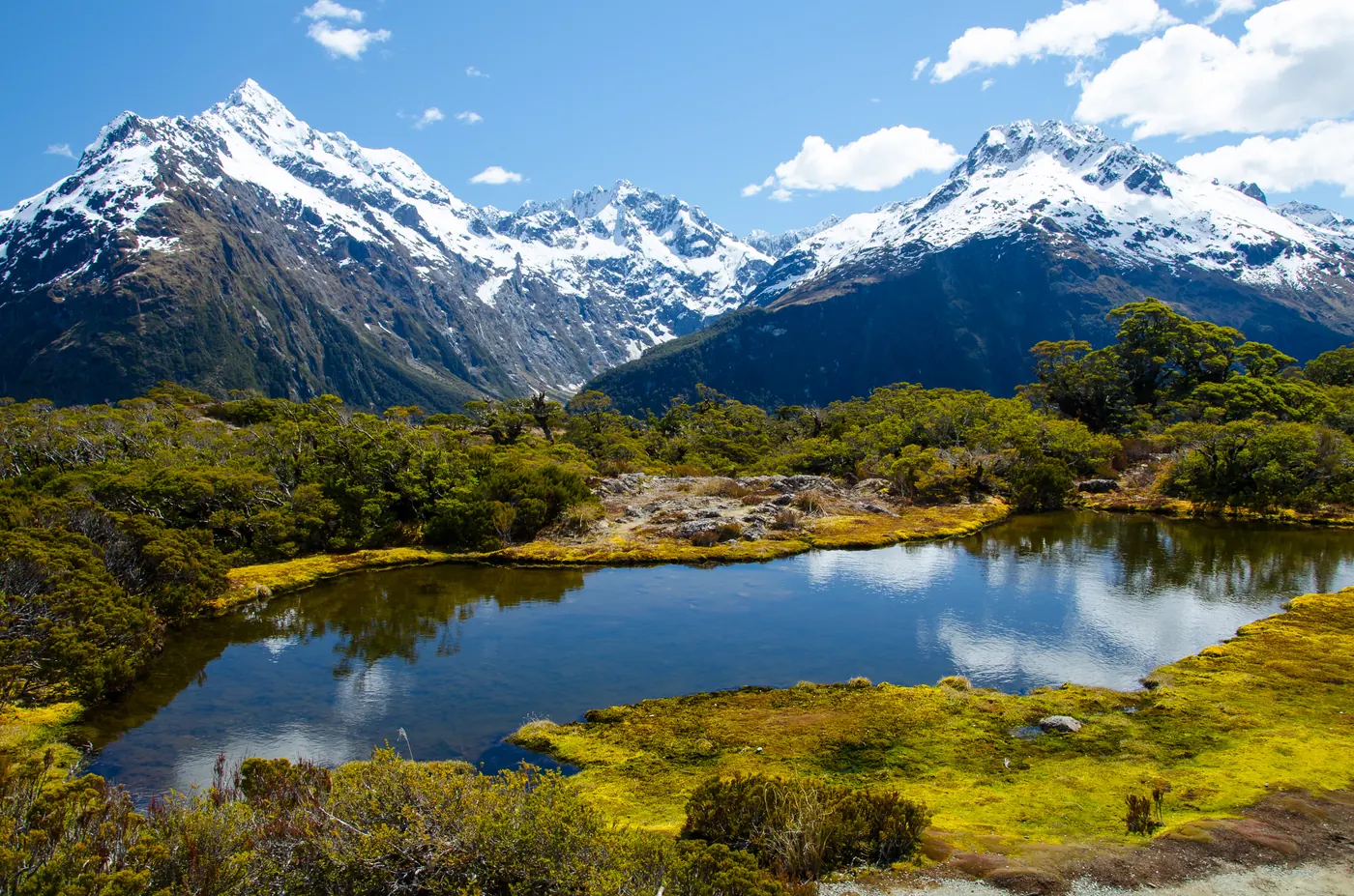 A small alpine tarn below snow-capped peaks