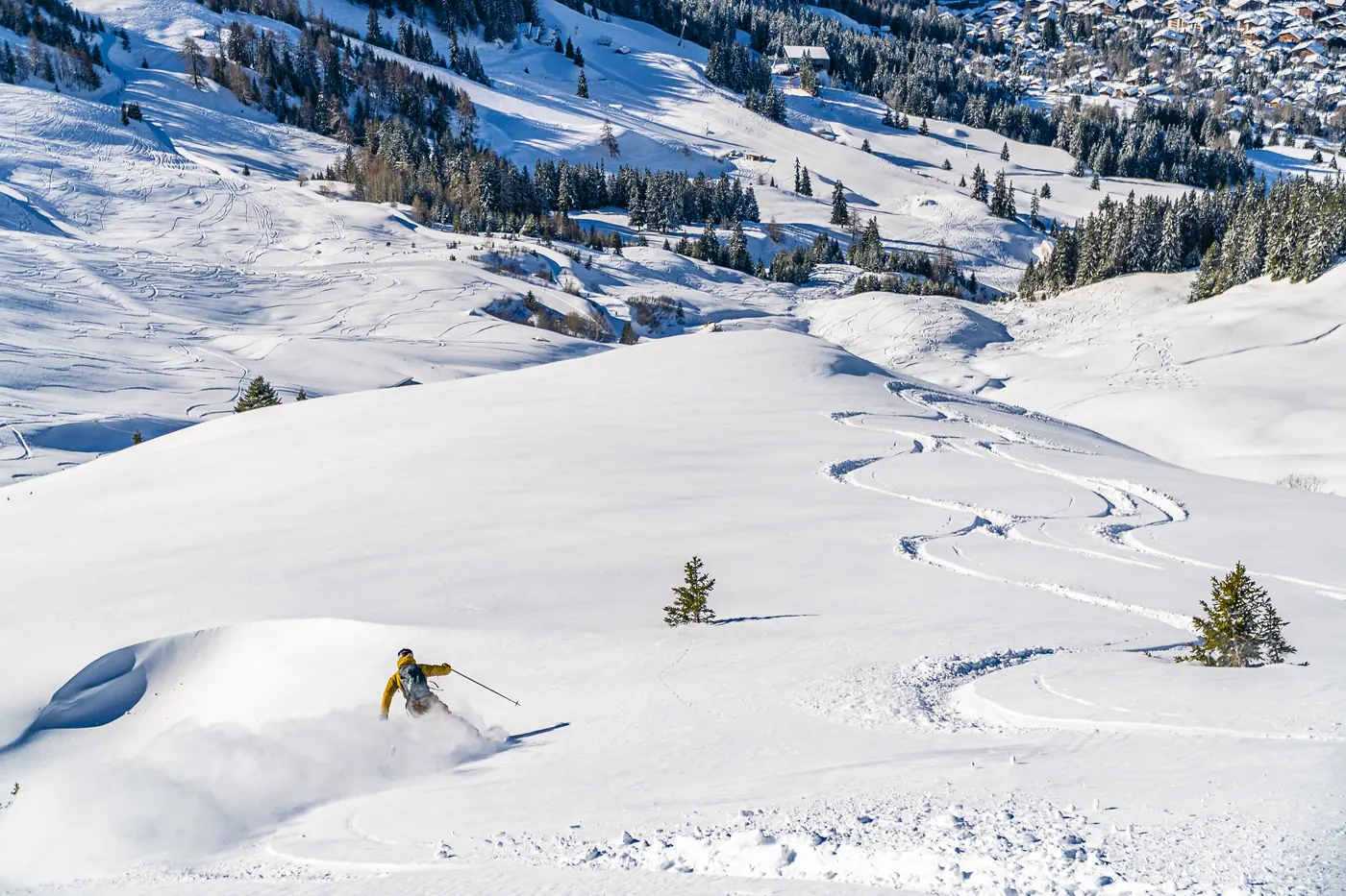 Skipiste mit Spuren und einem abfahrenden Skifahrer