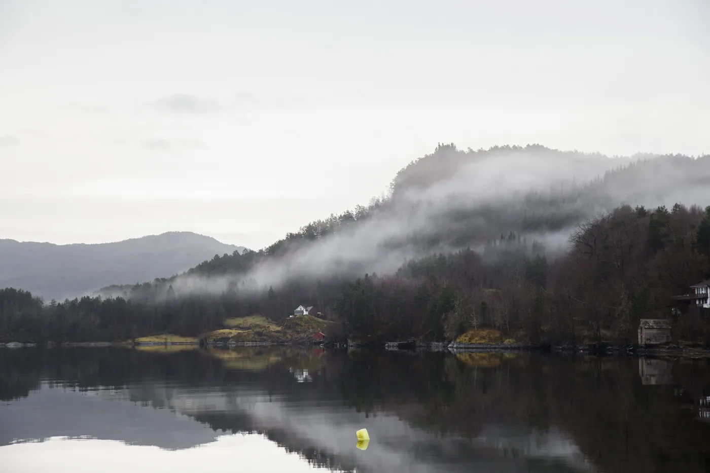 Low cloud over forested hills and a calm lake