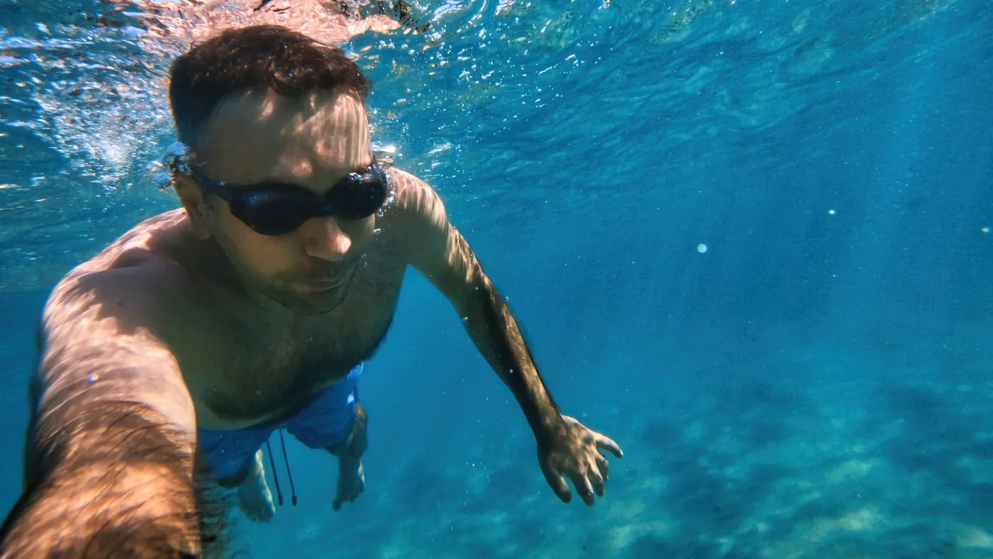 A swimmer in goggles underwater in clear blue water