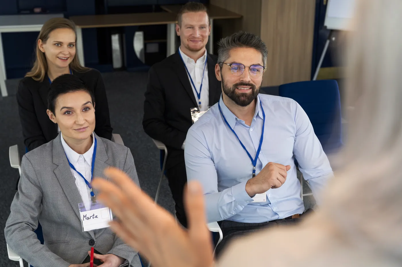 Delegates in lanyards listening to a speaker at a business event