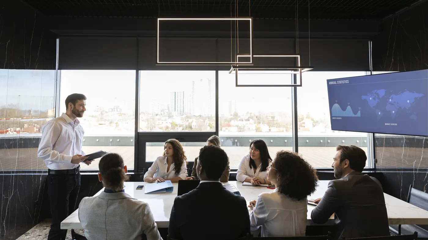 A presenter speaking to a group around a meeting table