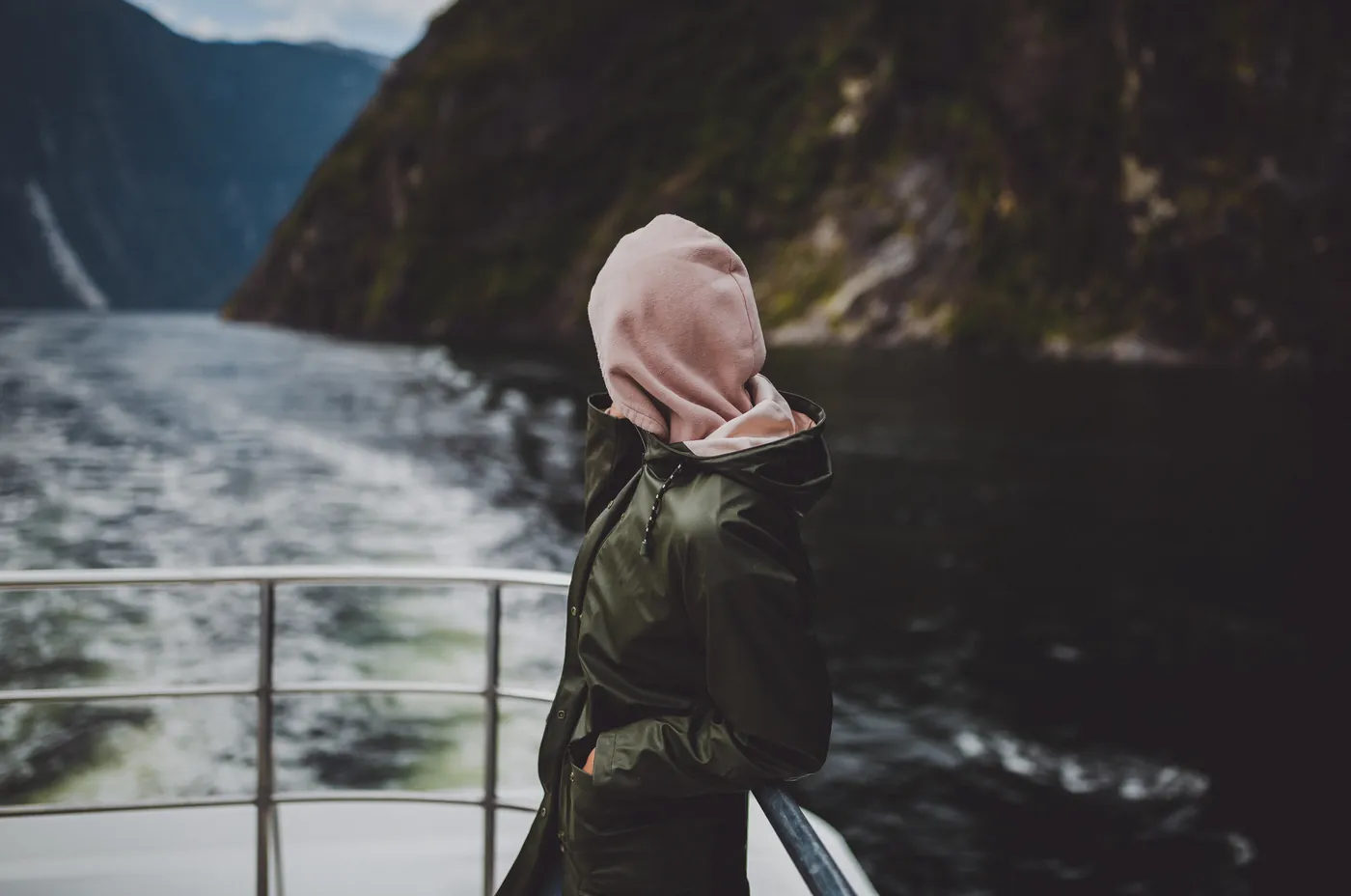 A traveller on the deck of a cruise boat in Milford Sound, New Zealand