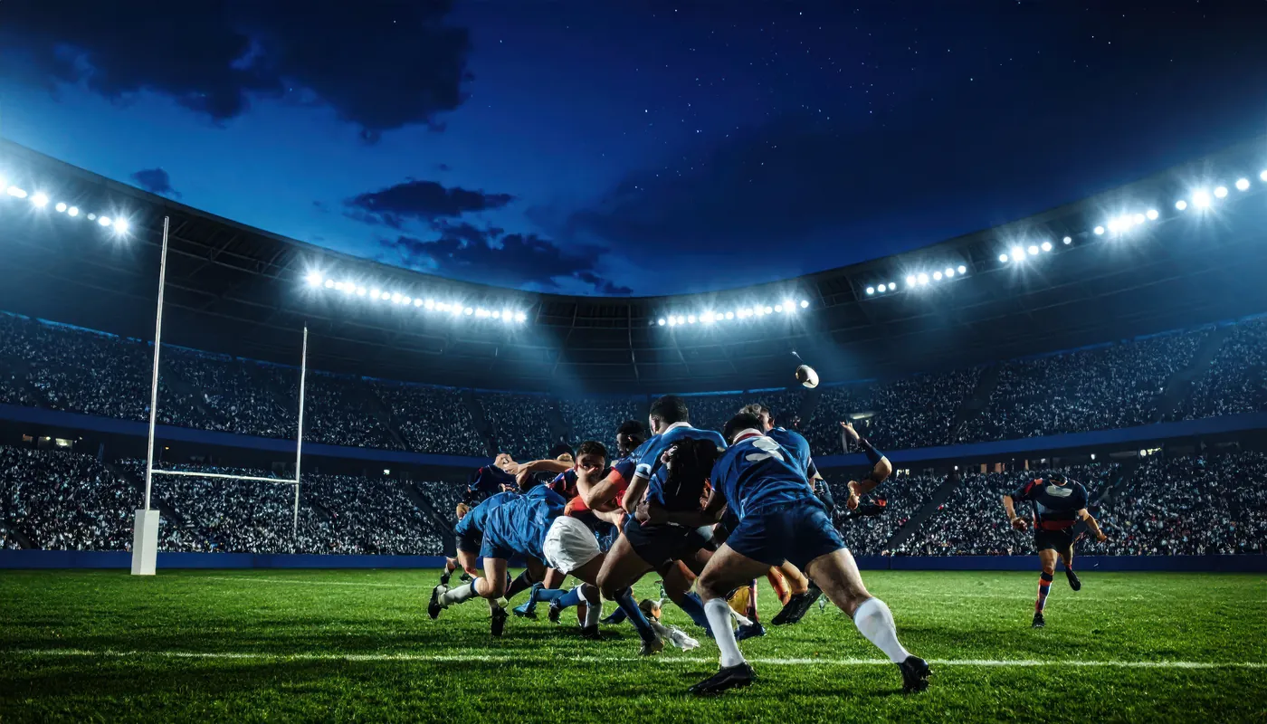 A rugby match under floodlights in a full stadium