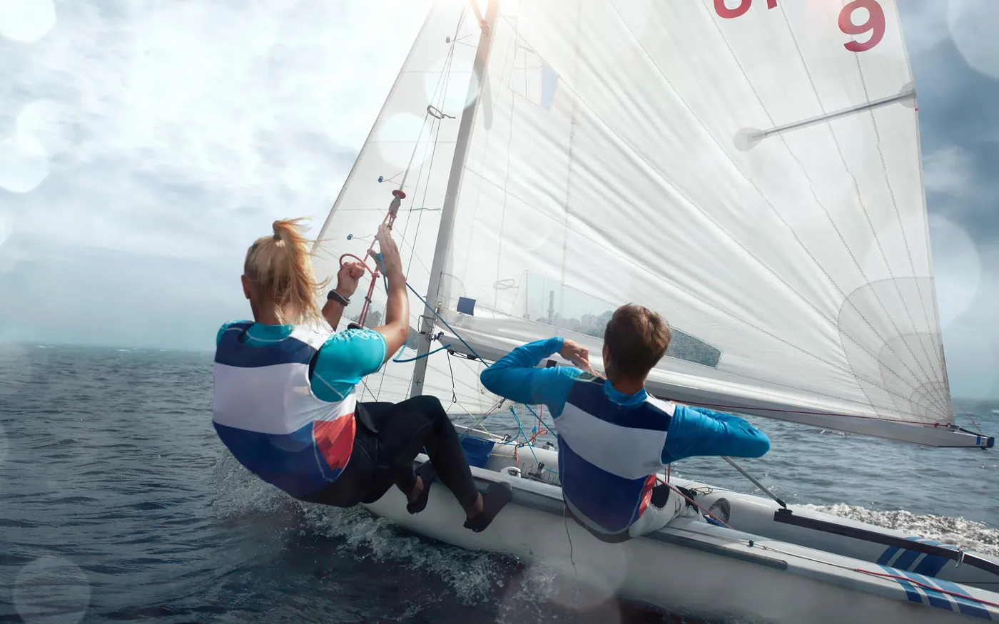 Two sailors leaning out from a small racing dinghy on open water