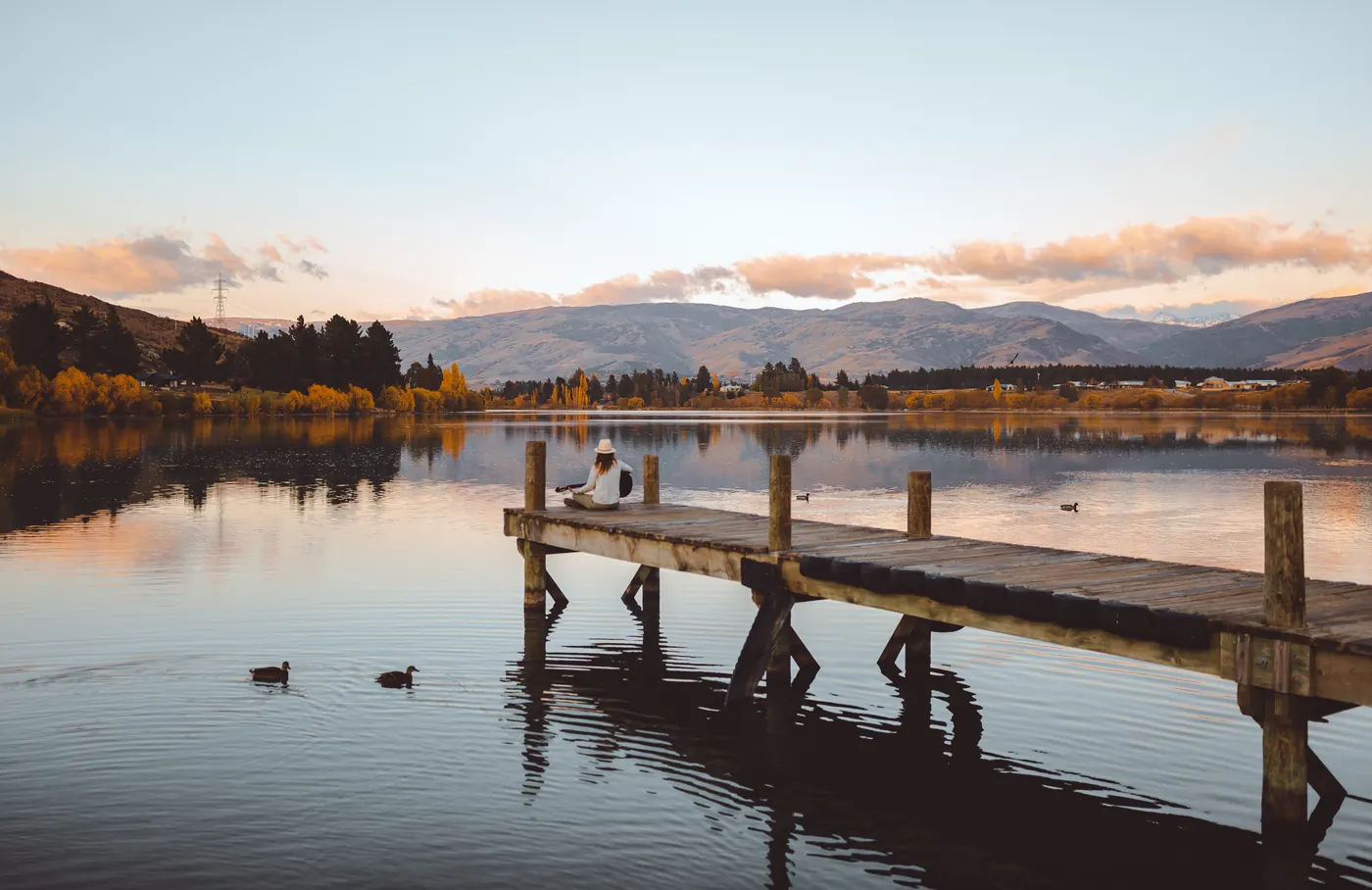 A woman sitting on a lakeside jetty at Cromwell in Central Otago