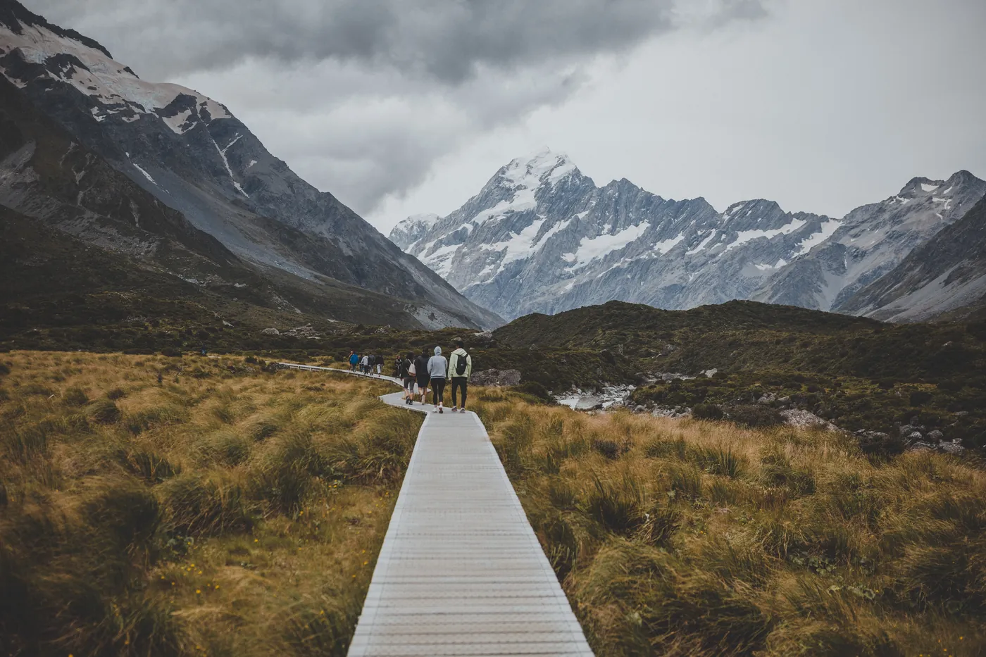 Walkers on a boardwalk in the Hooker Valley with Aoraki / Mount Cook ahead