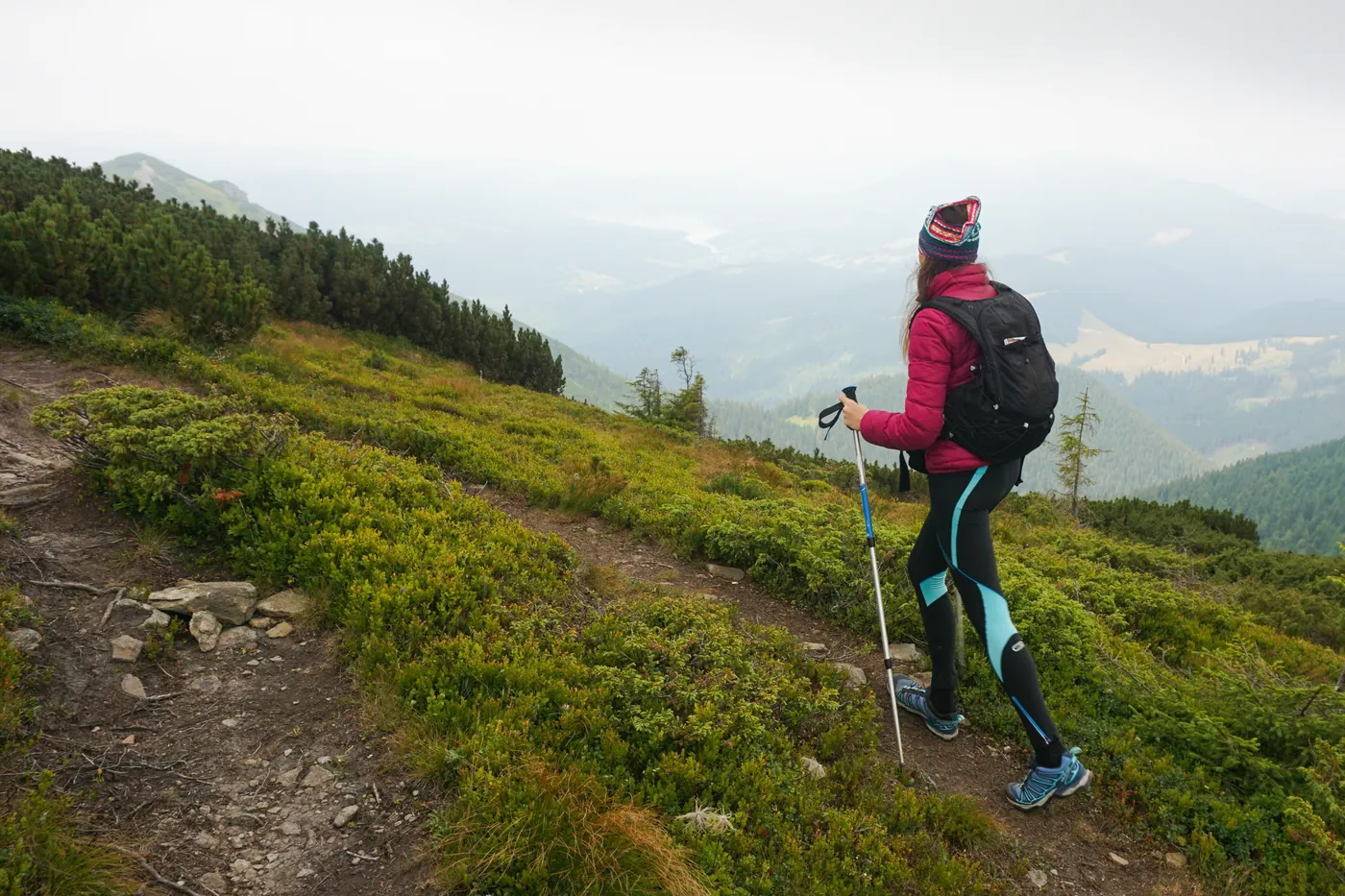 A walker with poles climbing a grassy slope in low cloud